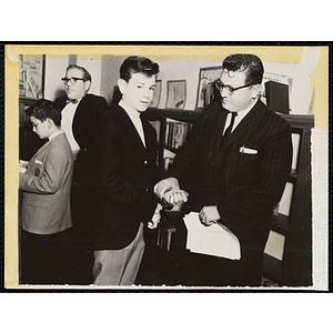 An unidentified man poses with a boy in handcuffs