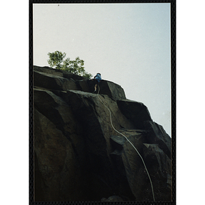 A child climbs a rock face attached to a climbing rope