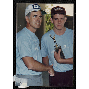 A teenage boy holds a trophy and shakes a man's hand during the Battle of Bunker Hill Road Race