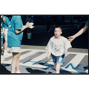A boy passes the finish line at the Battle of Bunker Hill Road Race