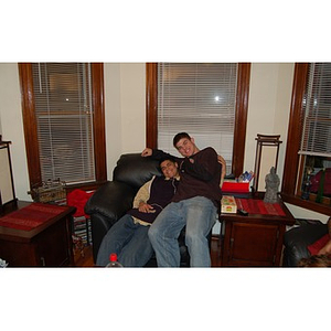 Danny Vazquez and Joseph Bordieri sit together on a chair at the Torch Scholars Thanksgiving Dinner