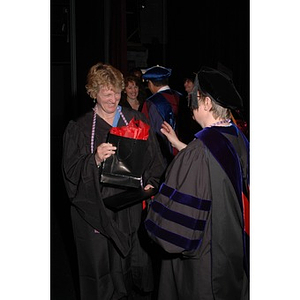 Faculty member presents student with certificate and gift bag at School of Nursing convocation