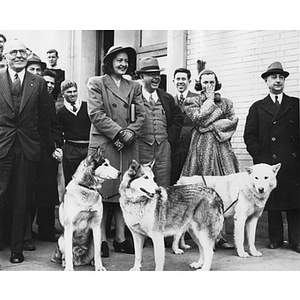 A woman holds three dogs on leashes at the coronation of King Husky II