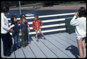 Girl taking a picture of children standing on dock