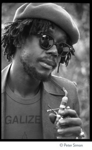 Peter Tosh: portrait wearing beret, dark glasses, and a Legalize it tee shirt, smoking a pipe