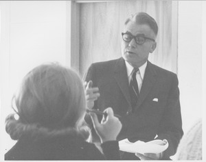 Bert T. Combs standing indoors, speaking to female student