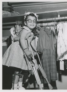 Young girl on crutches looking at dresses