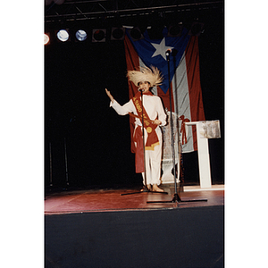 A woman in a Gurabo sash speaks into a microphone at the Festival Puertorriqueño