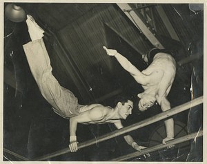 Two male gymnasts performing on the parallel bars