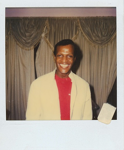 A Photograph of Marsha P. Johnson Smiling in a White Button Up Over a Red Shirt