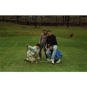 A man rides on another man's shoulders as two others pose at a Boys and Girls Club Golf Tournament