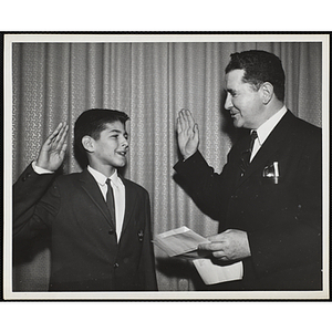 An unidentified man offers an oath to a boy