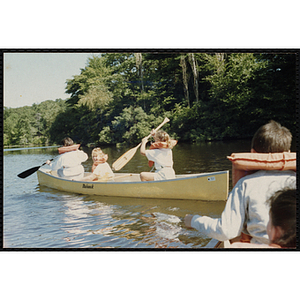 Children in canoes paddle on a lake