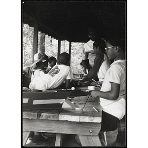 A group of youth stand around a craft table with a supervisor