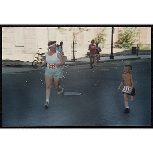 A boy runs alongside a woman during the Battle of Bunker Hill Road Race