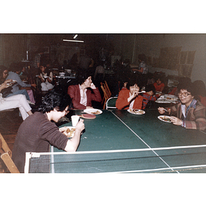 Young women sit at a ping-pong table and talk while enjoying a tutoring dinner