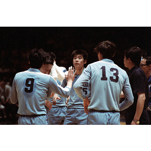 Members of the Men's Chinese Volleyball Team stand in a huddle during a game with the United States Men's Volleyball Team