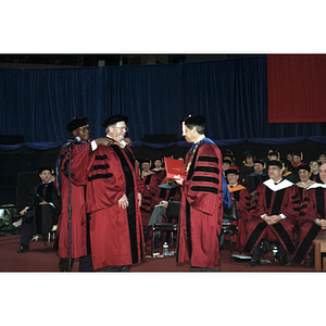 Escort Harry T. Daniels places the hood on honorary degree recipient Neal F. Finnegan