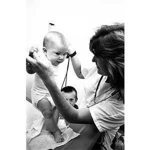 Nursing student, baby, and young child during medical examination