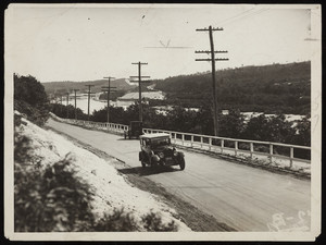 Two cars drive on the road alongside the Cape Cod Canal