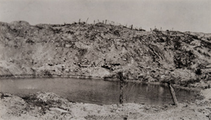 Ground-level view of a large shell hole filled with water