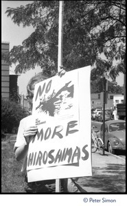 Protester at a Mobilization for Survival antinuclear demonstration near Draper Laboratory, MIT, with sign reading 'Fund human needs: No more Hiroshimas'