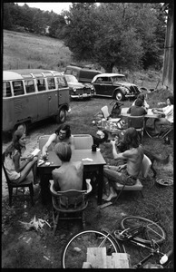 Susan Mareneck (far left), Steve Marsden (with beard), and friends seated at a card table in front of Montague Farm Commune