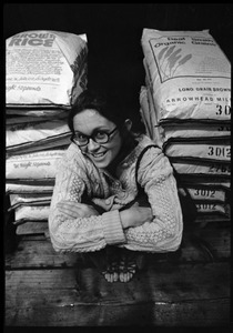 Woman crouched by sacks of brown rice, at Erewhon Trading Company