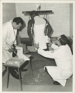 Two technicians make a plaster cast of a double amputee's body