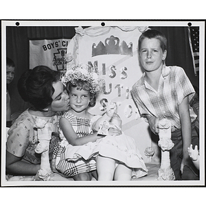 Mary Ann Mobley, Miss America 1959, kisses the Little Sister Contest winner on the cheek as her brother leans on her throne