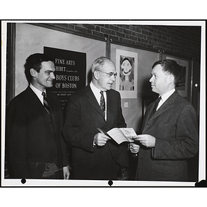 "Co-Chairman, Richard H. Bassett, Head of the Art Dept. of Milton Academy, discusses the Art Guide with Overseers, William B. Osgood and Stokley P. Towles at a preview of the Boys' Clubs of Boston's Art Exhibit"