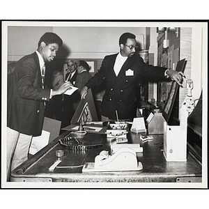 Roscoe Baker, Roxbury Boys' Club director, at right, and an unidentified man prepare for the Boys' Clubs of Boston Art Exhibit