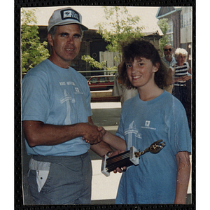 A man shakes runner Susan Burke's hand and presents her with a trophy during the Battle of Bunker Hill Road Race