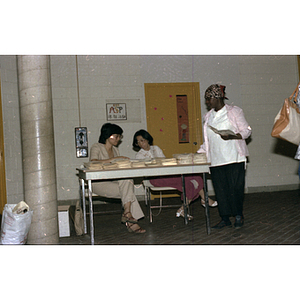 Woman holds a brochure next to Chinese Progressive Association's information booth