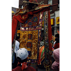 Crowd surrounds a man holding a decorative banner during a parade celebrating the Chinese New Year in Boston's Chinatown