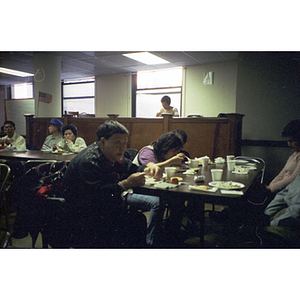 Members of the Chinese Progressive Association sit at tables eating Thanksgiving dinner