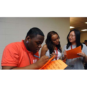 Ulysses Ifill, Melanie Arvajo, and Qinrui Pang look at orange sheets of paper