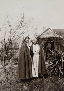 Two Red Cross workers standing outside in a garden