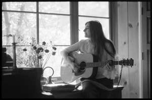 Judy Collins seated in a window, playing guitar in Joni Mitchell's house in Laurel Canyon