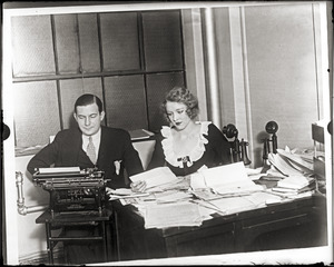Mark Hellinger, seated at his desk with his wife Gladys Glad Hellinger