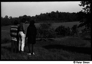 Marty Jezer (in poncho), Raymond Mungo, and Michelle Clarke, backs to camera, looking out over the fields