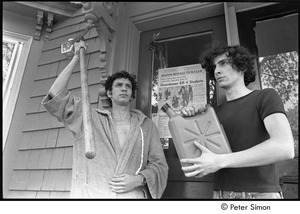 David Doubilet holding a shovel and Stephen Davis holding a gasoline can, standing in front of the Boston Herald Traveler front page reporting the Kent State Shooting