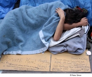 Occupy Wall Street: man sleeping by sign asking for donations and listing supernatural creatures