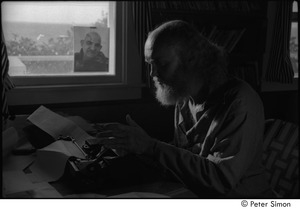 Ram Dass at typewriter: Ram Dass typing, with a portrait of Neem Karoli Baba in the background