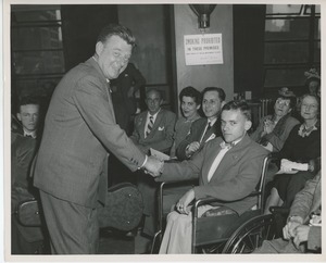 Arthur Godfrey shaking hands with client in wheelchair at Institute Day