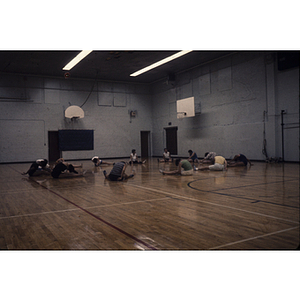 People stretching in a circle on the floor of a gymnasium