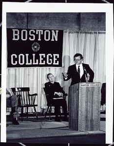 Ted Kennedy speaking at Boston College event, Father Monan in background