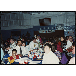 Children and adults, seated together, look to the front during a Kiwanis Awards Night