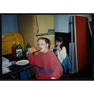 Boy and girl eating pizza slices at a table