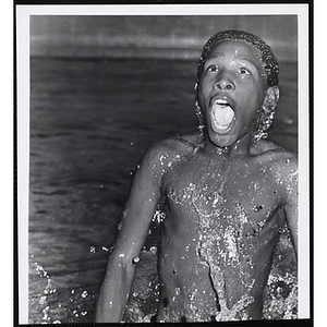 A boy emerges from the water of a pool
